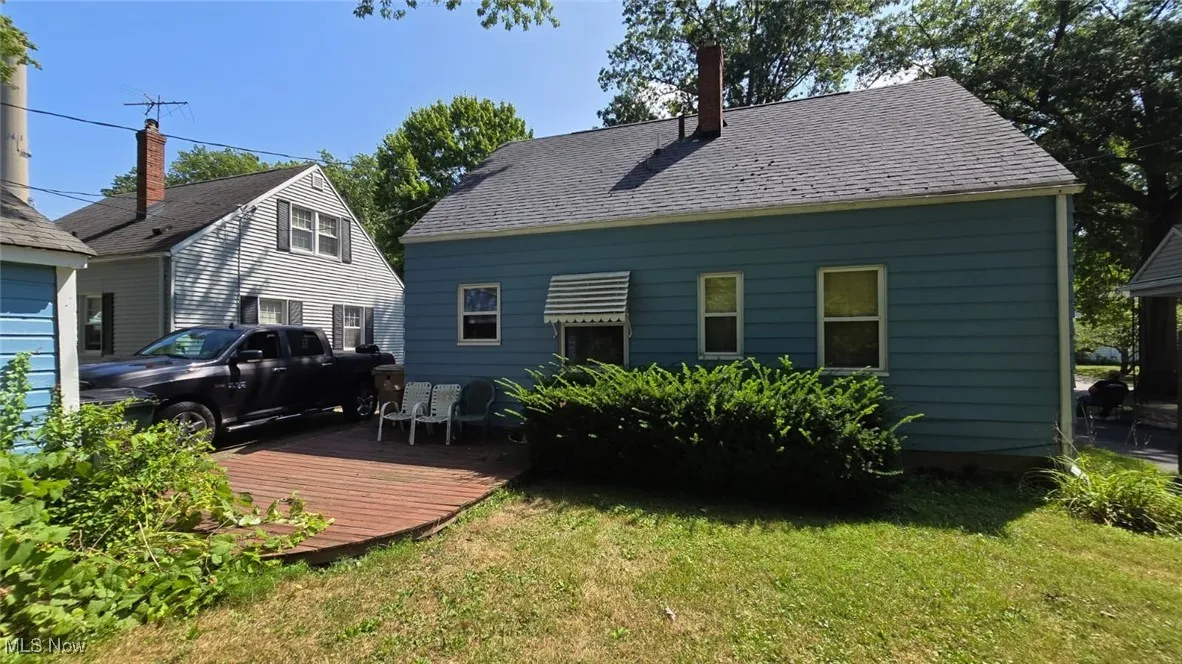 Back of property featuring a yard, a deck, and roof with shingles