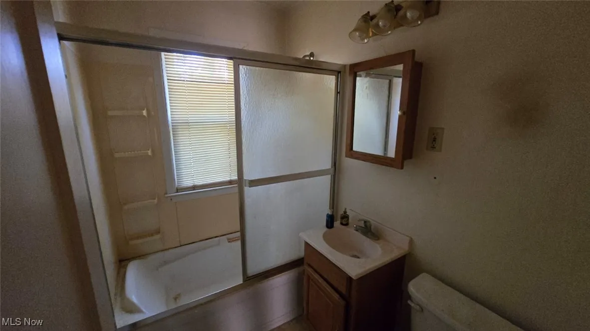 Full bath featuring combined bath / shower with glass door and vanity