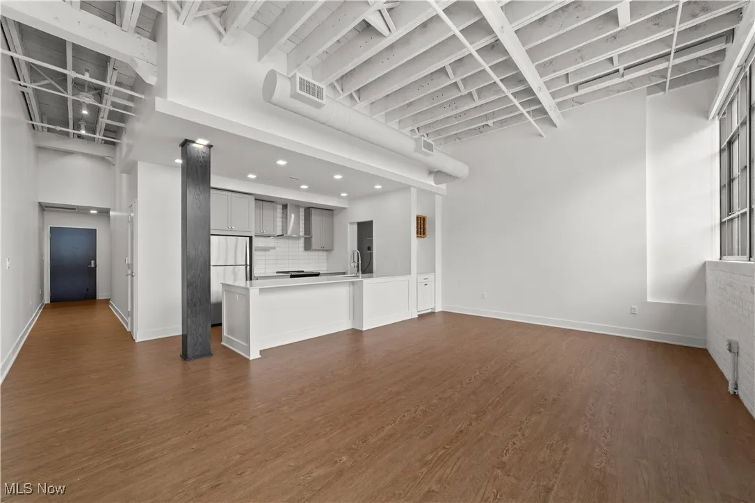 View of kitchen and entry from living room with tall ceilings and exposed beams
