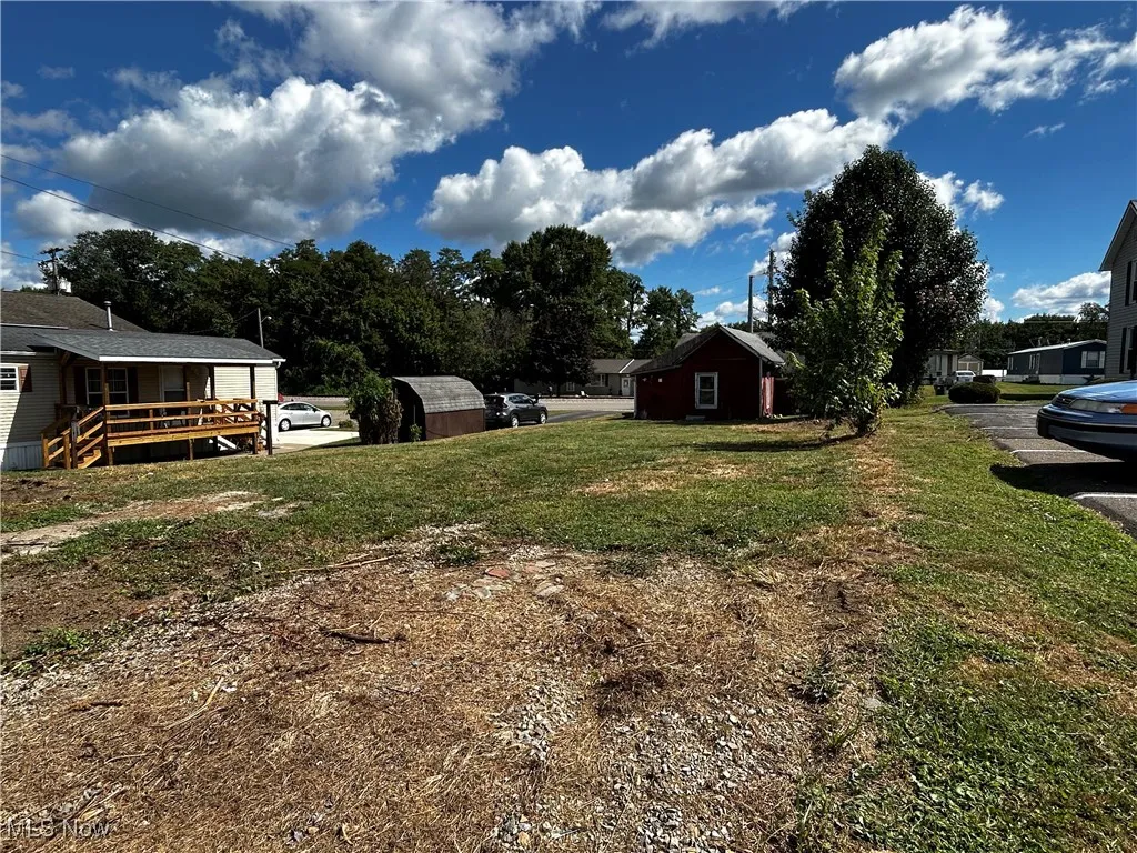 View of green lawn featuring a deck and an outbuilding