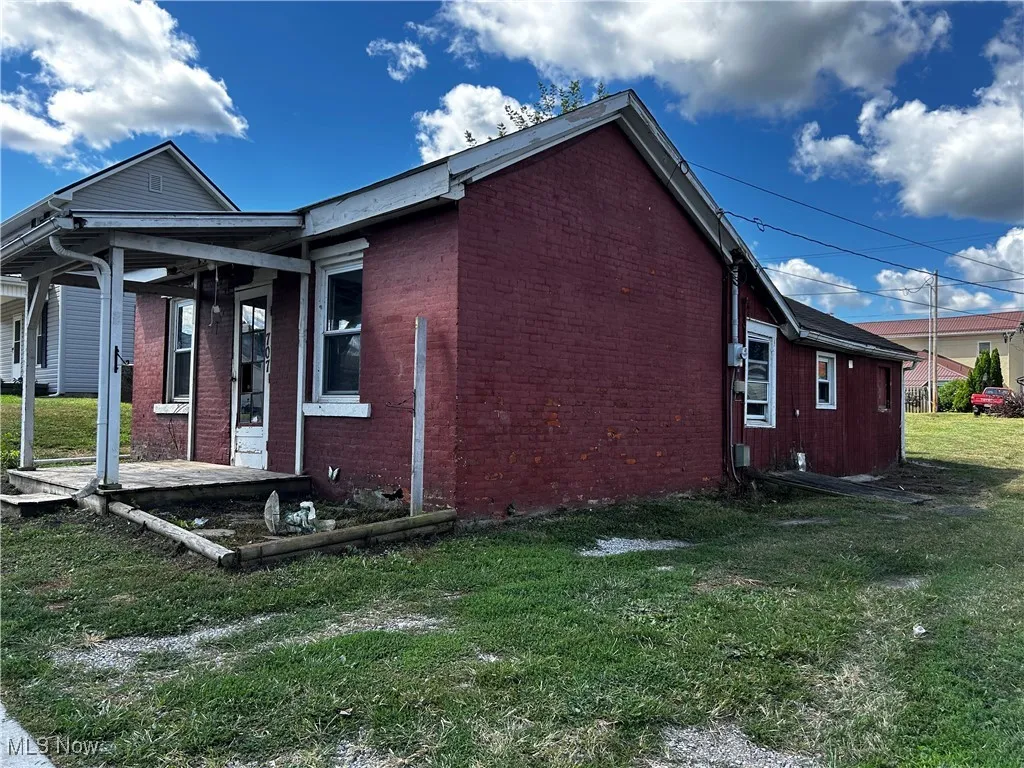 View of side of property with a lawn and brick siding