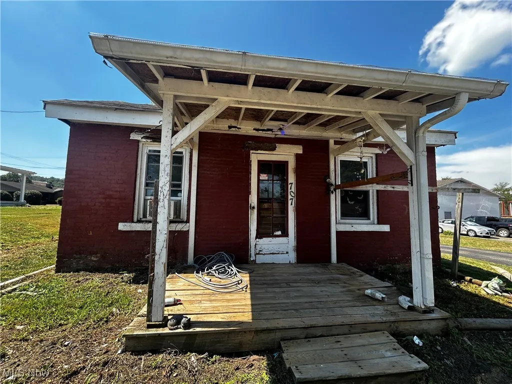 Entrance to property with brick siding and a porch