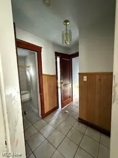 Corridor with light tile patterned floors, wood walls, and wainscoting