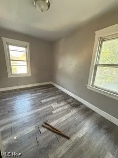Empty room featuring dark wood-type flooring and baseboards