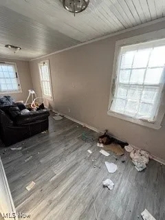 Unfurnished living room featuring wood finished floors and crown molding