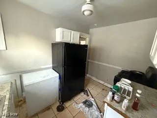 Kitchen featuring white cabinets, freestanding refrigerator, and light tile patterned floors