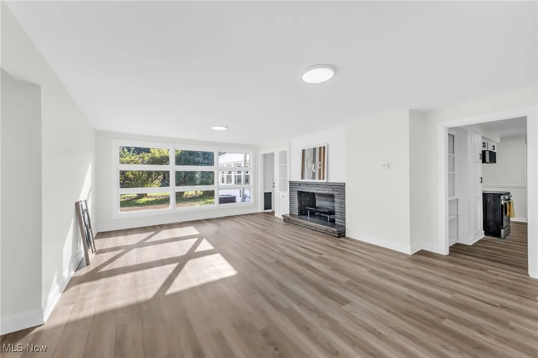 Unfurnished living room featuring light wood-type flooring and a fireplace with raised hearth