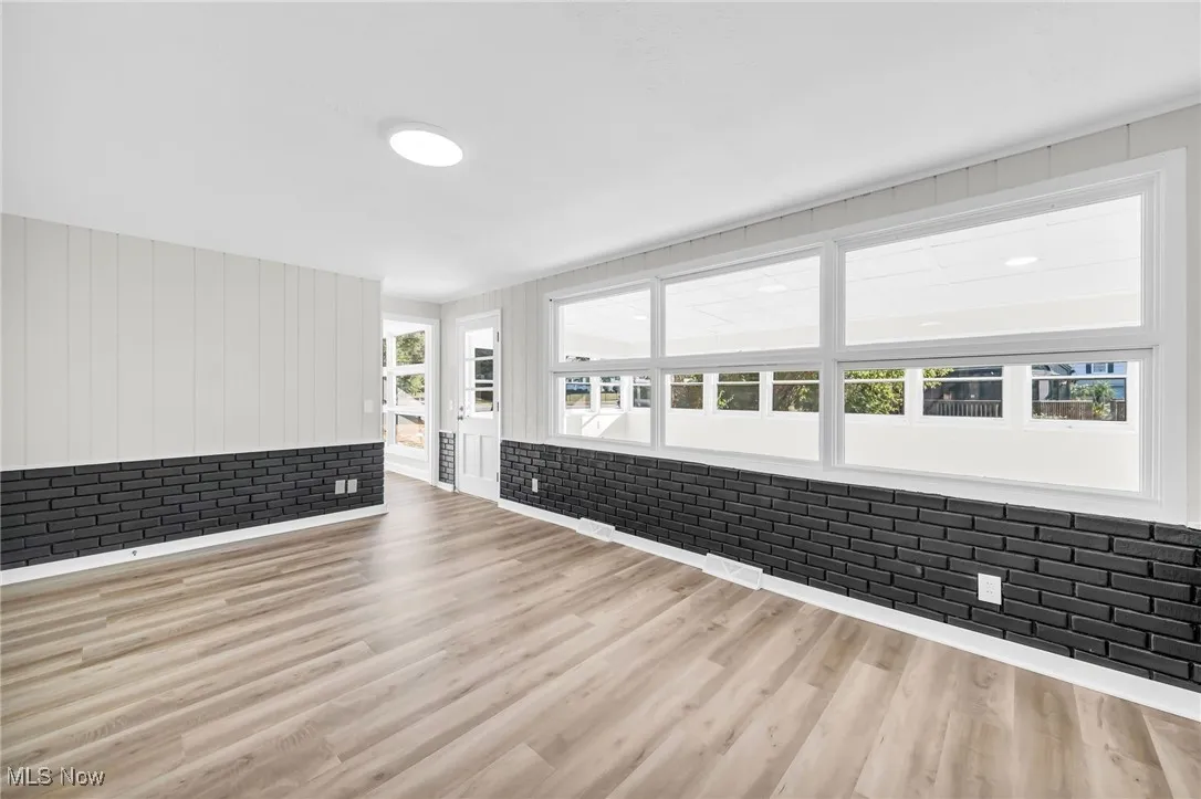 Unfurnished living room with wood finished floors and brick wall