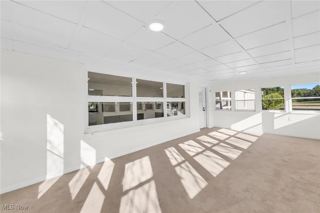 Unfurnished sunroom with carpet floors and a paneled ceiling