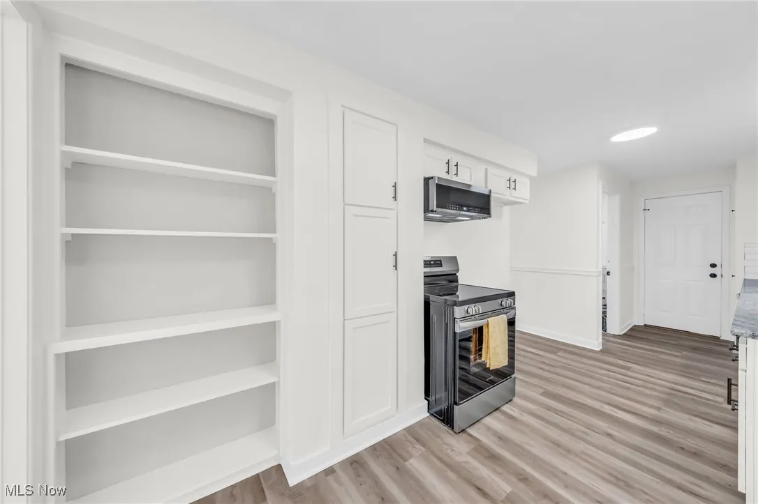 Kitchen with appliances with stainless steel finishes, white cabinetry, light wood finished floors, and recessed lighting