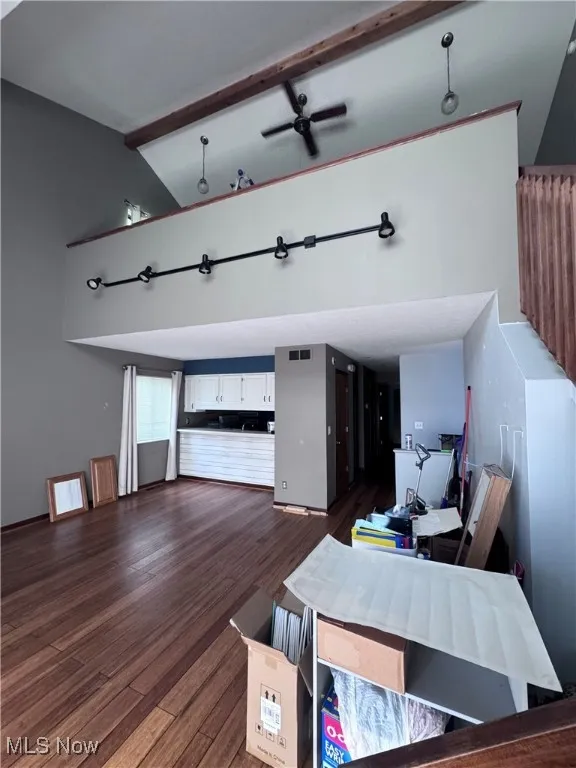 Living area with beamed ceiling, ceiling fan, high vaulted ceiling, and dark wood-style floors
