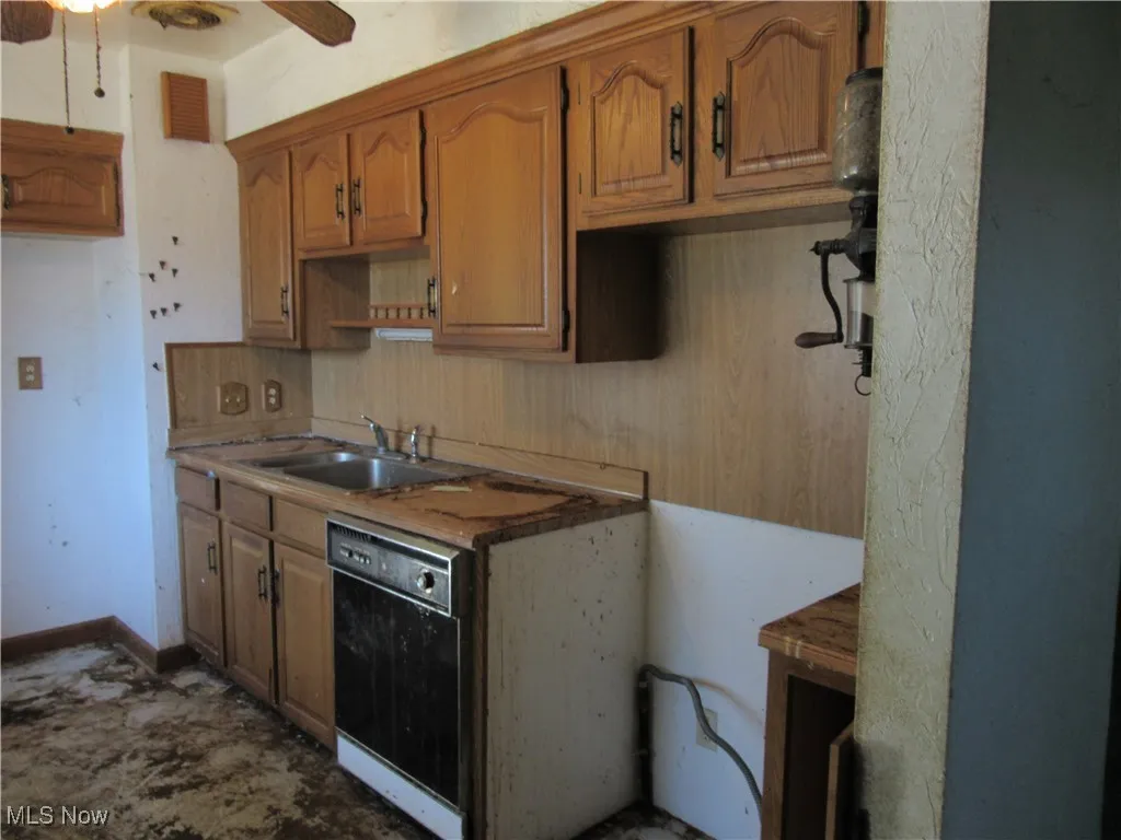 Kitchen with brown cabinets, a ceiling fan, black dishwasher, and light countertops