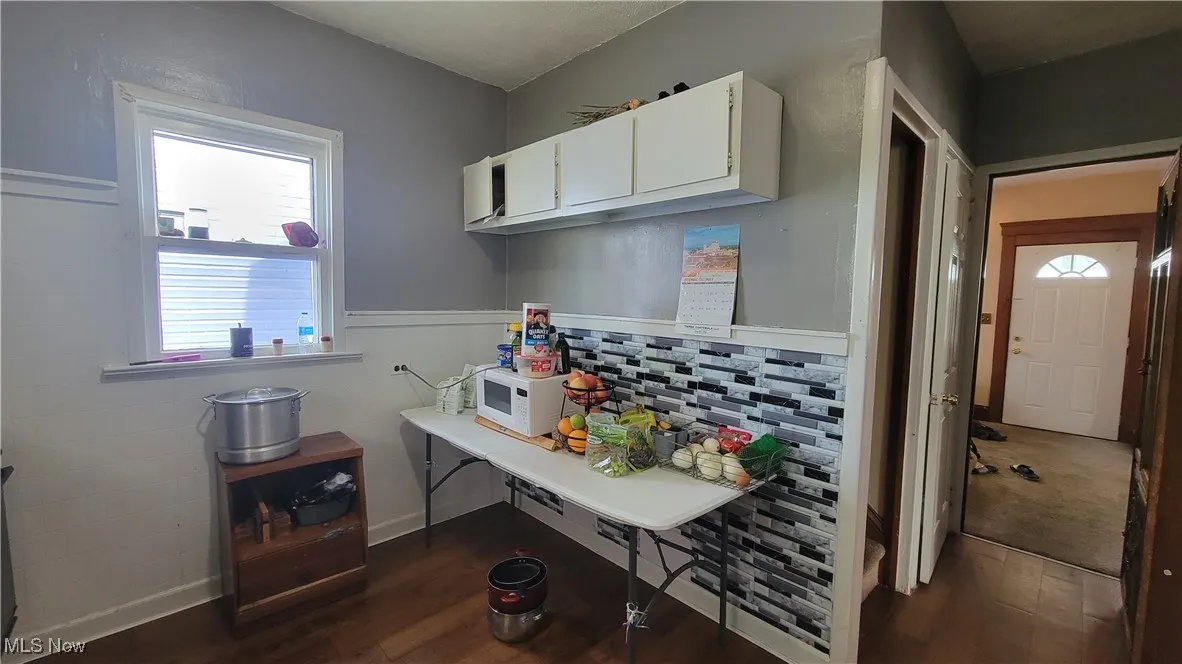 Kitchen with white cabinetry, plenty of natural light, a wainscoted wall, dark wood-style flooring, and tile walls