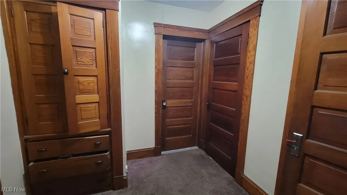 Hallway with dark carpet and baseboards