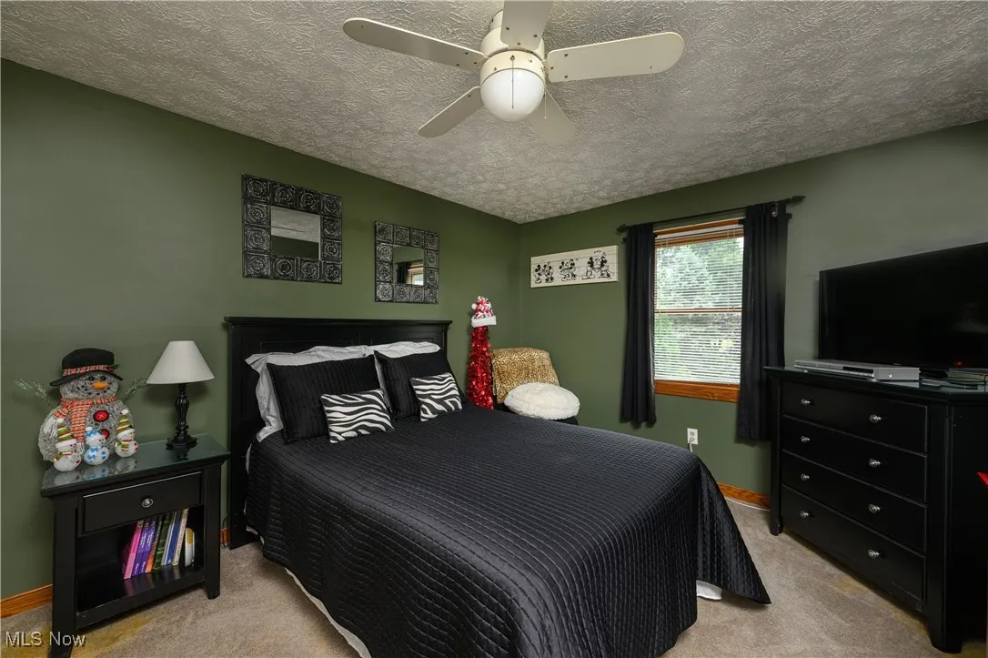 Bedroom with light colored carpet, a textured ceiling, and ceiling fan