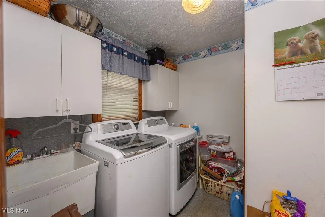 Laundry area with a textured ceiling, cabinet space, and washing machine and dryer