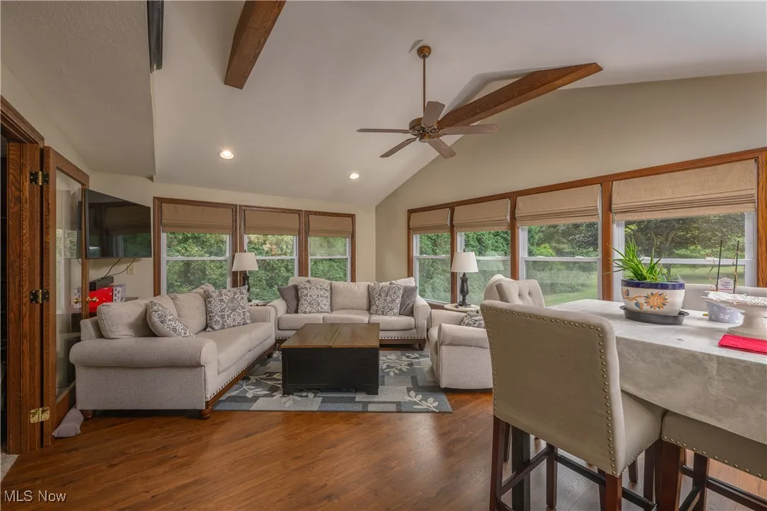 Living room with beam ceiling, dark wood finished floors, high vaulted ceiling, recessed lighting, and ceiling fan