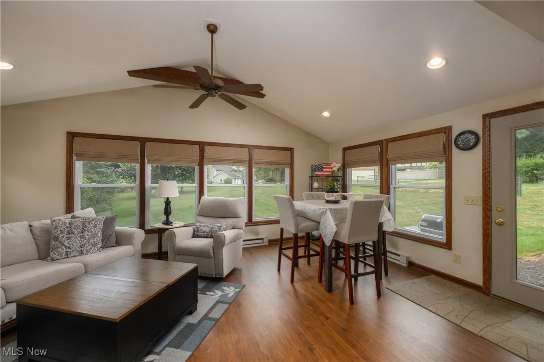Living area featuring recessed lighting, wood finished floors, vaulted ceiling, a ceiling fan, and baseboard heating