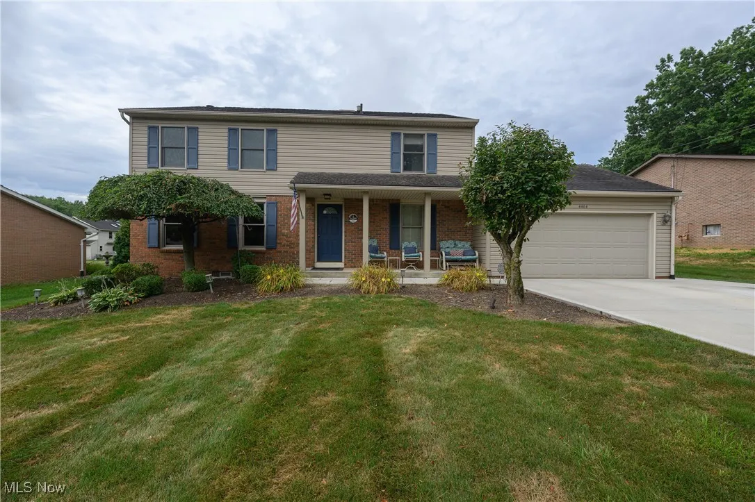 Traditional-style house featuring covered porch, an attached garage, brick siding, driveway, and a front lawn