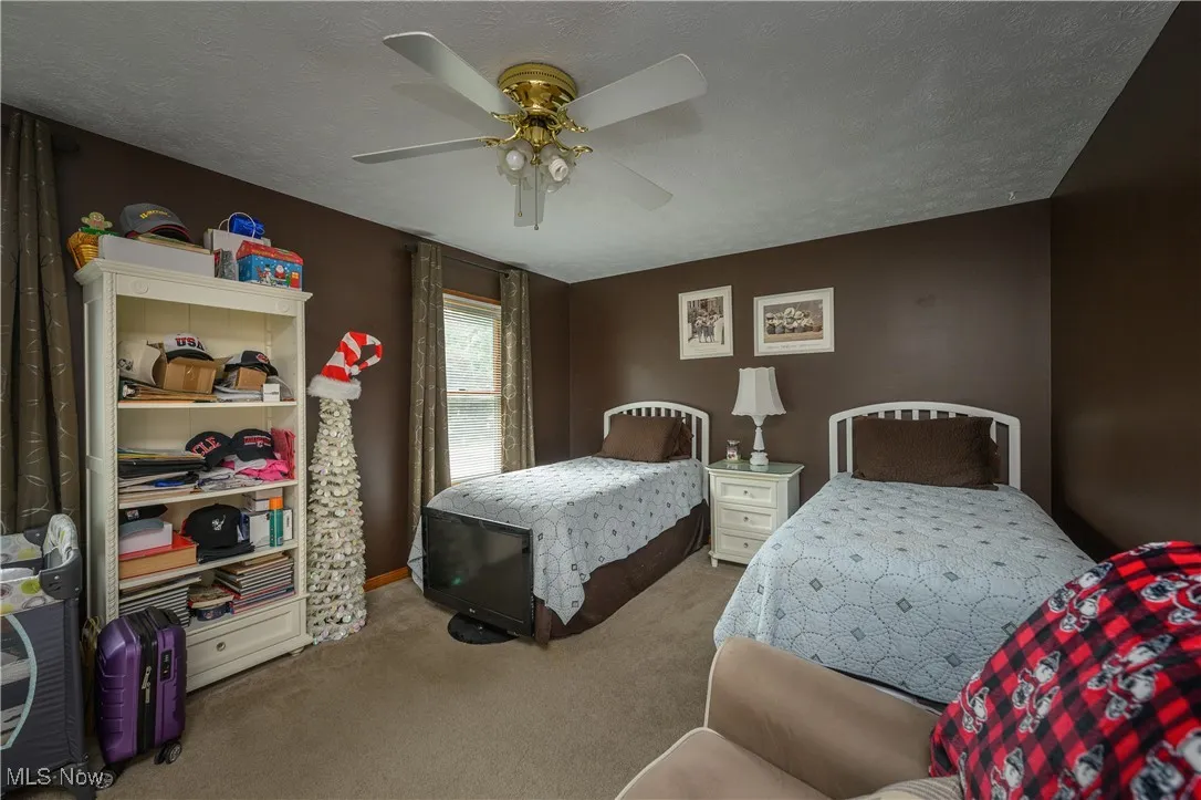 Carpeted bedroom featuring a textured ceiling and a ceiling fan