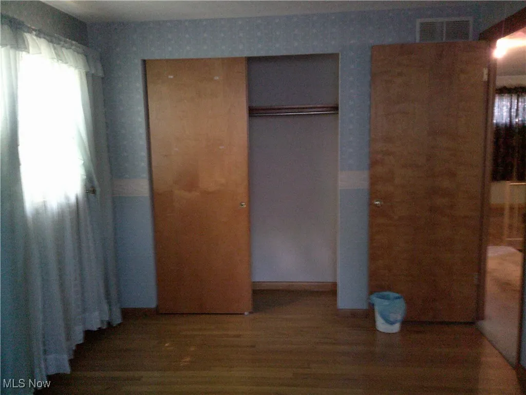 Unfurnished bedroom with wood finished floors and a closet