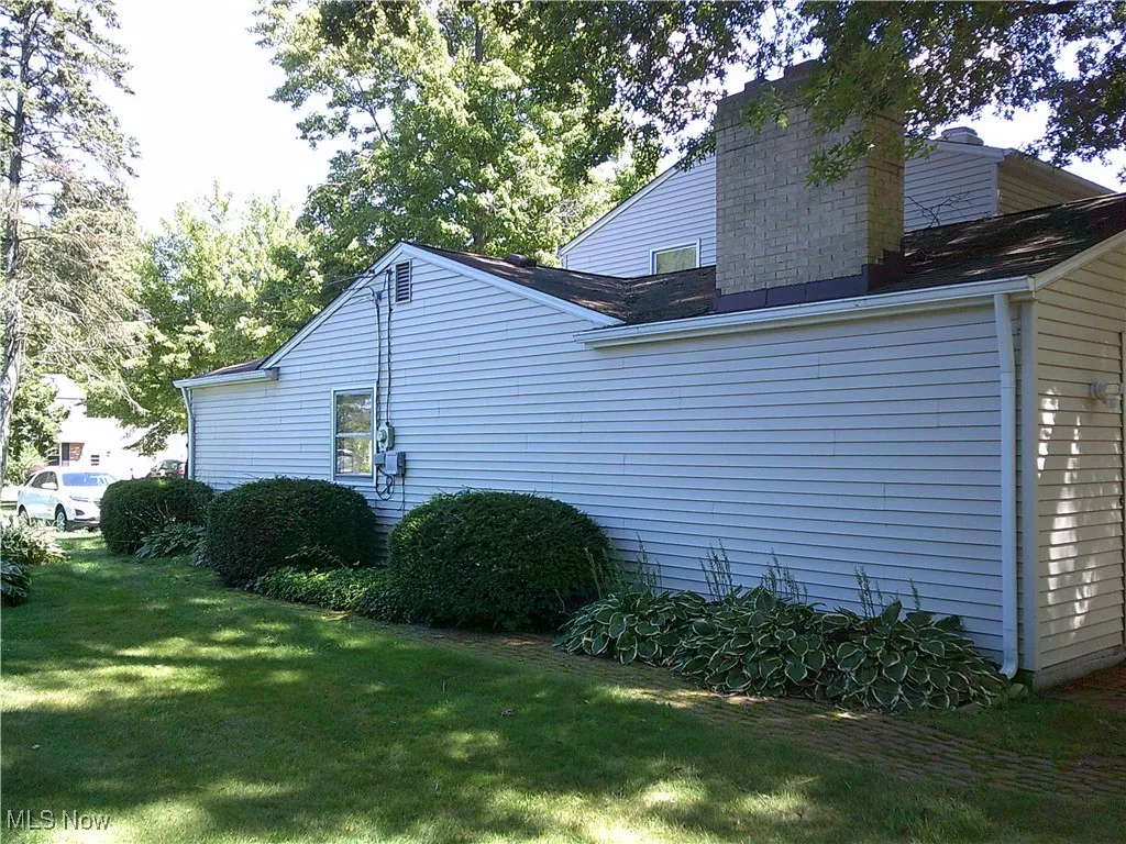 View of side of home with a lawn and a chimney