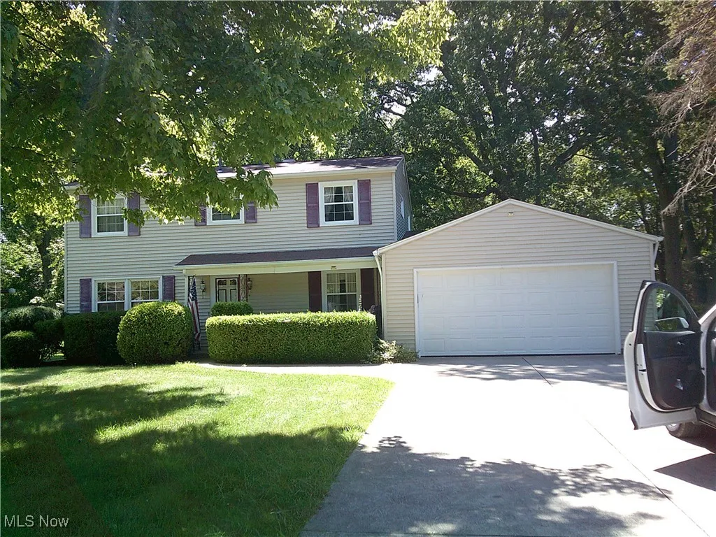 View of front facade with covered porch, driveway, an outdoor structure, and a front yard
