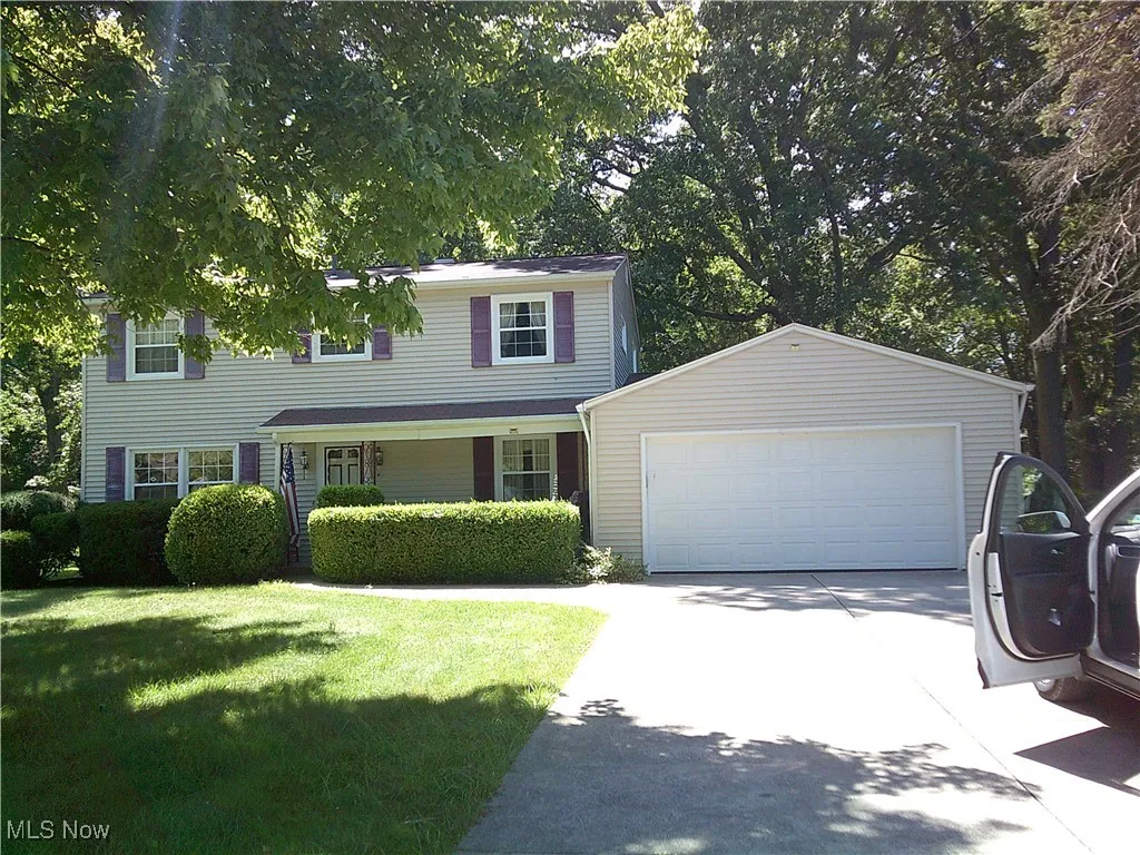 View of front of property with a garage, covered porch, driveway, an outdoor structure, and a front yard