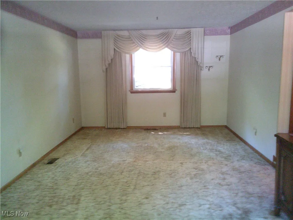 Unfurnished room featuring carpet and baseboards