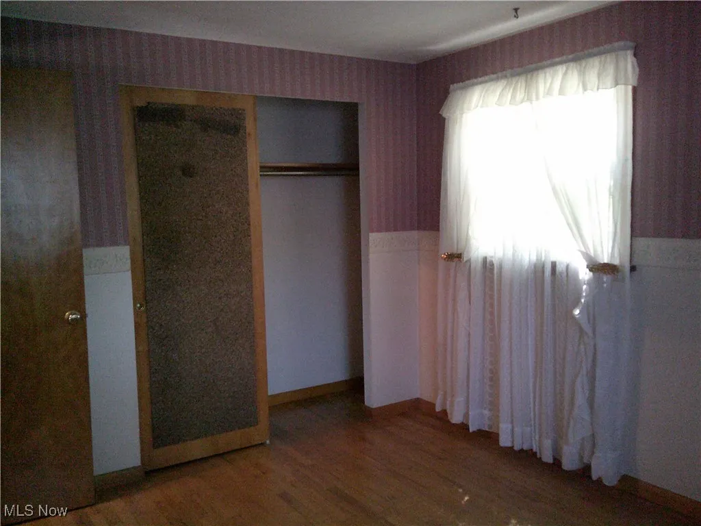 Unfurnished bedroom with dark wood-style flooring and a closet