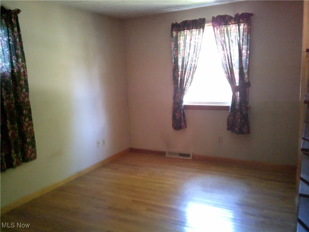 Unfurnished room featuring wood finished floors and baseboards