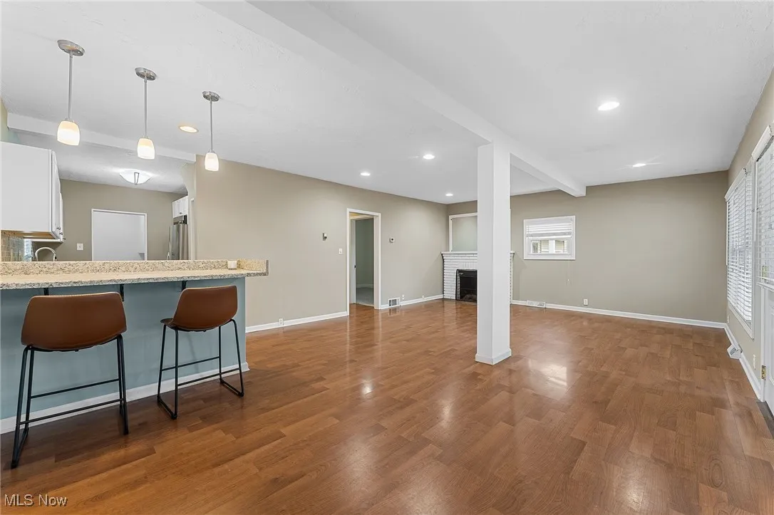 Unfurnished living room featuring a brick fireplace, dark wood finished floors, recessed lighting, and beam ceiling