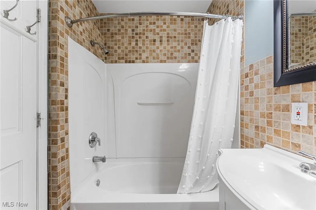 Full bath with tile walls and shower / tub combo with curtain