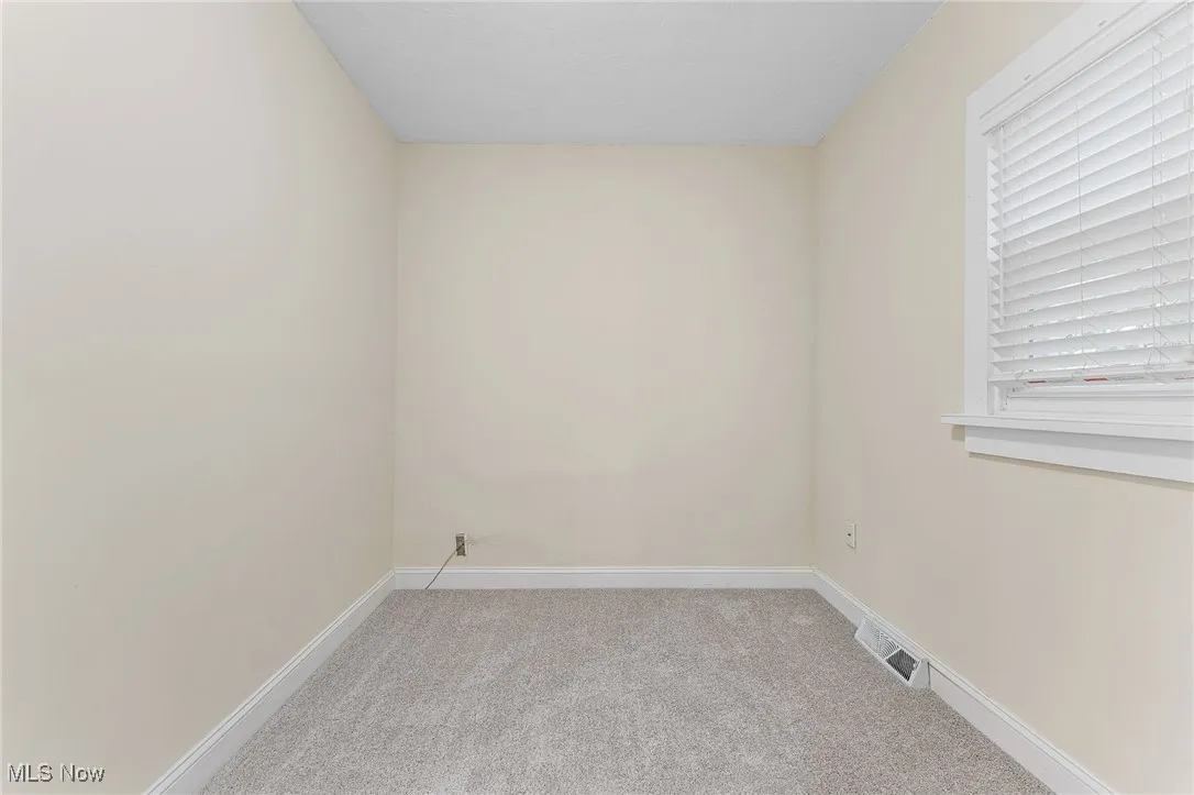 Spare room with light carpet and baseboards