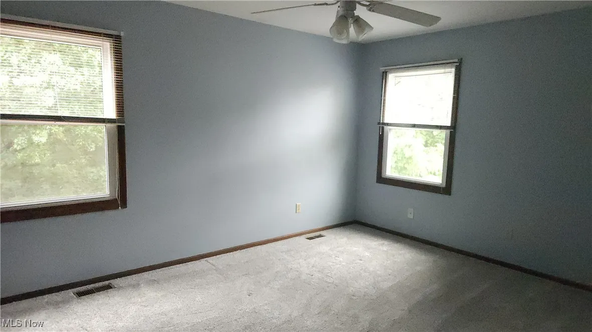 Carpeted empty room with baseboards and a ceiling fan
