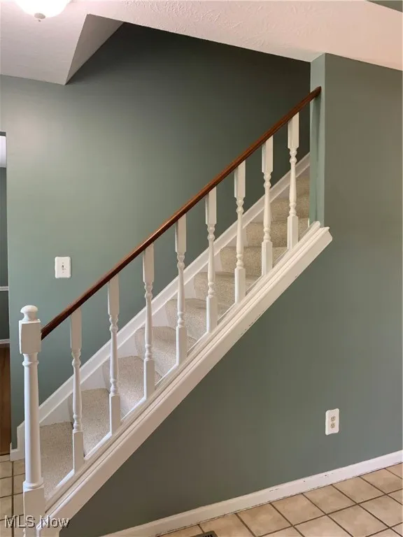 Stairway with tile patterned flooring and baseboards