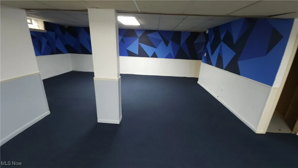 Finished below grade area featuring a paneled ceiling and dark carpet