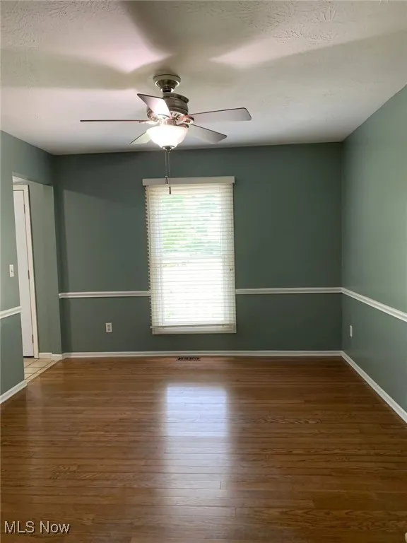 Spare room with a textured ceiling, dark wood-style flooring, and ceiling fan