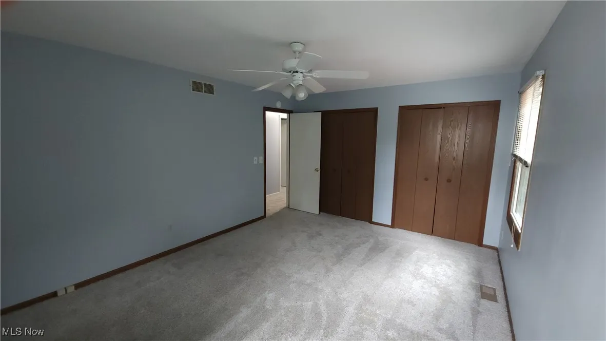 Unfurnished bedroom featuring multiple closets, carpet, and a ceiling fan