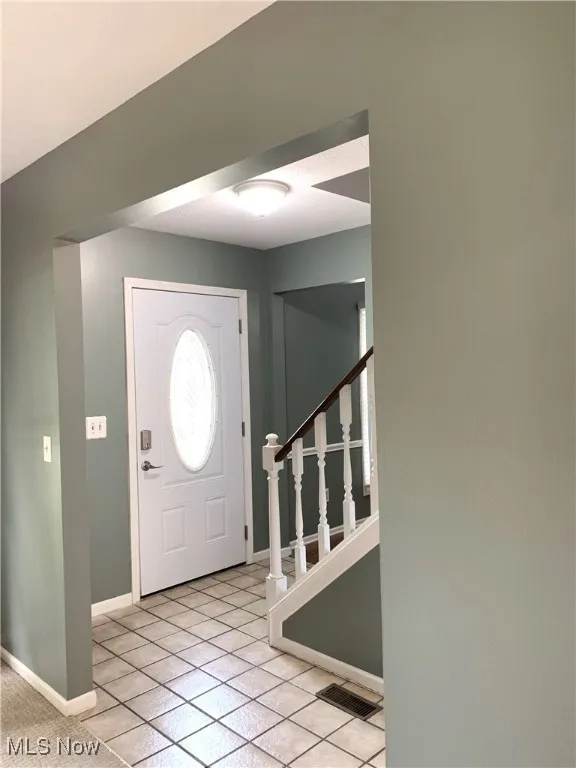 Entryway featuring stairs and light tile patterned floors