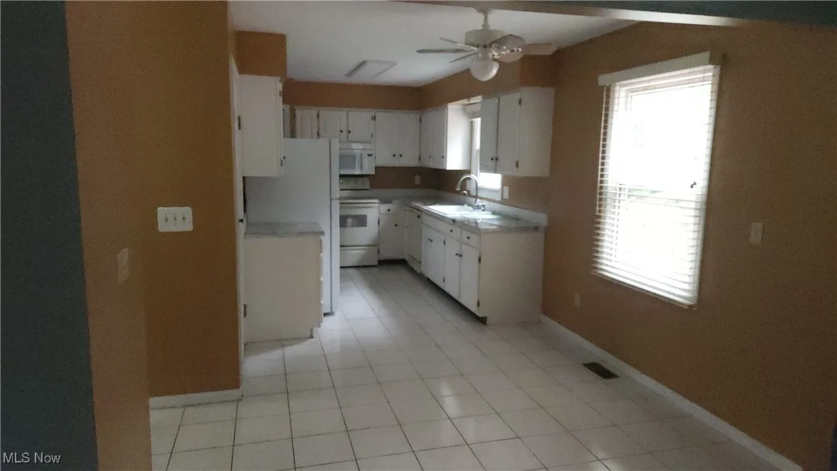 Kitchen featuring white cabinetry, light countertops, and white appliances