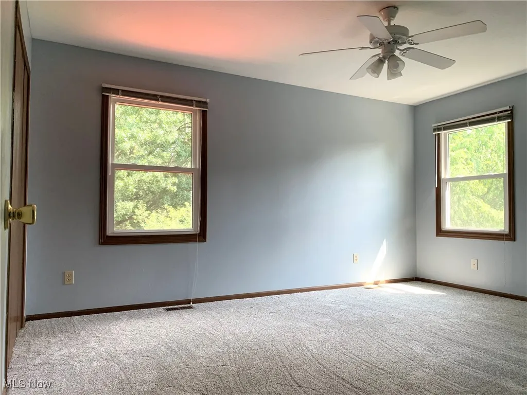 Carpeted empty room with baseboards and ceiling fan