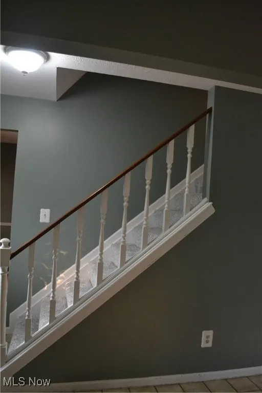 Stairs with tile patterned flooring and baseboards