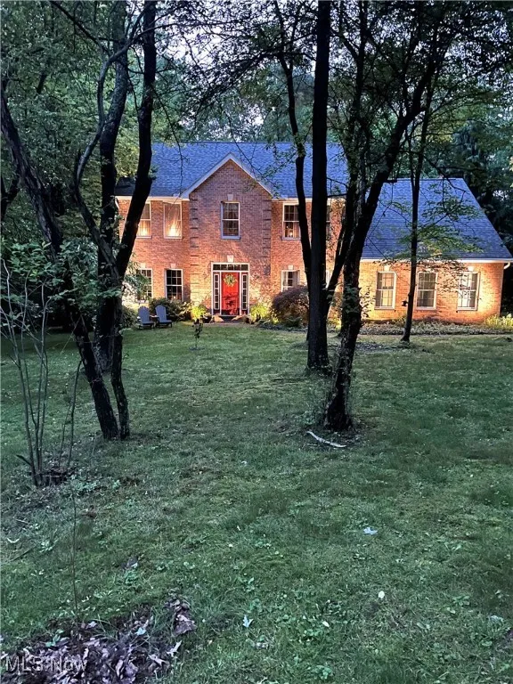 Colonial-style house featuring a front yard and brick siding