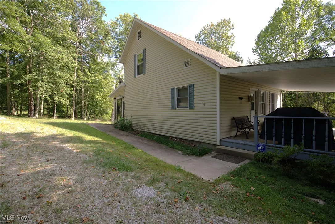 View of side of property with a yard and a wooden deck