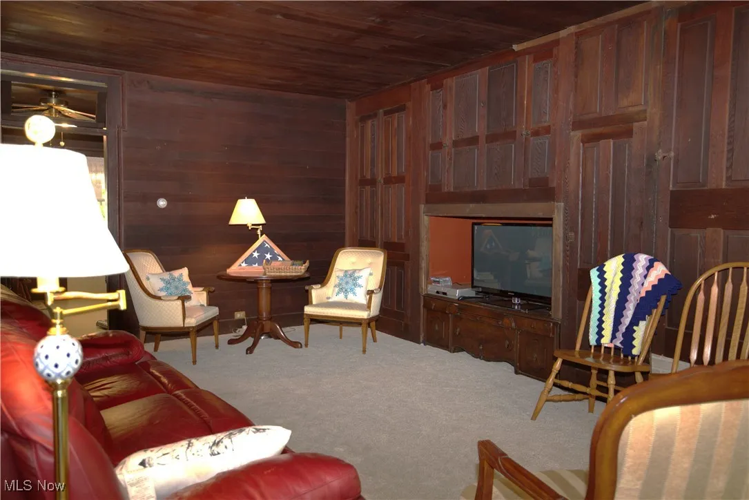 Living room with wood ceiling, wood walls, and carpet flooring