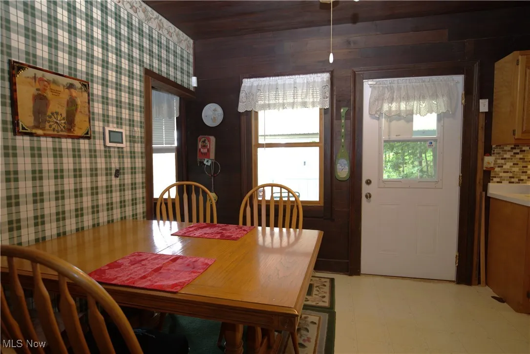Dining room featuring light flooring, wooden ceiling, and wallpapered walls