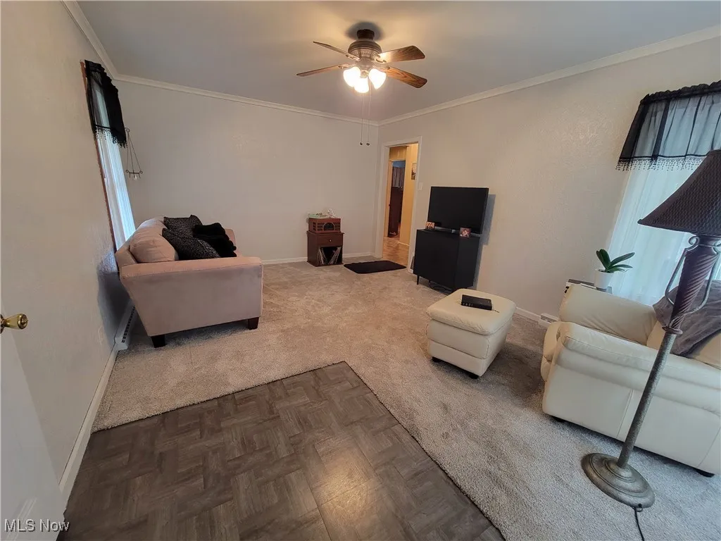 Living area featuring crown molding, plenty of natural light, and a ceiling fan