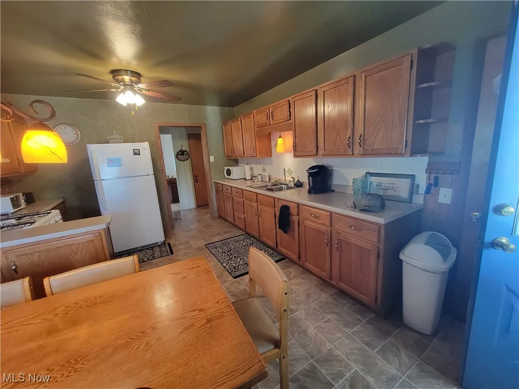 Kitchen with white appliances, open shelves, light countertops, and ceiling fan