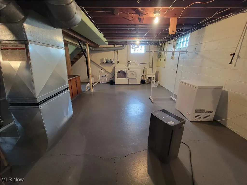 Below grade area with heating unit and washing machine and clothes dryer